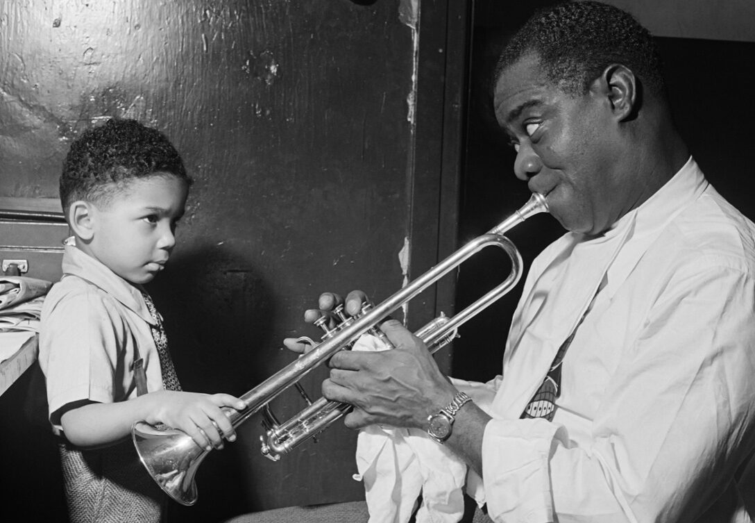 1G08V4_SCHWAB-ÉRIC-SCHWAB-Le-jazzman-américain-Louis-Armstrong-joue-pour-un-petit-garçon-dans-sa-loge,-avant-un-spectacle-en-1947-dans-un-cabaret-de-jazz-de-New-York-cropped