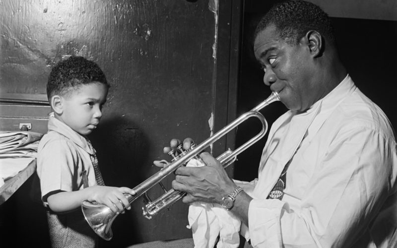 1G08V4_SCHWAB-ÉRIC-SCHWAB-Le-jazzman-américain-Louis-Armstrong-joue-pour-un-petit-garçon-dans-sa-loge,-avant-un-spectacle-en-1947-dans-un-cabaret-de-jazz-de-New-York-cropped